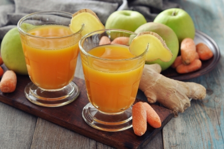 Apple and carrot juice in glass with ginger,  fresh vegetables and fruits on wooden trayの写真素材