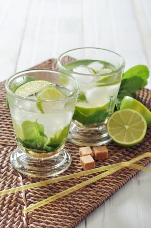 Mojito cocktail in glass with lime and mint on wicker place matの写真素材
