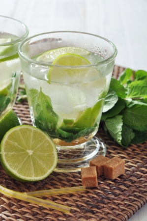 Mojito cocktail in glass with lime and mint on wicker place matの写真素材