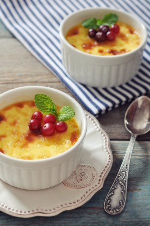 The creme brulee in ceramic baking mold with mint and berries on wooden tableの写真素材