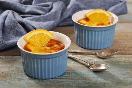 The creme brulee in ceramic baking mold with orange on wooden tableの写真素材