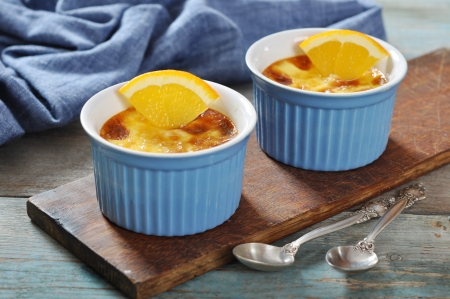 The creme brulee in ceramic baking mold with orange on wooden tableの写真素材