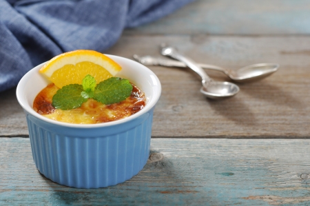 The creme brulee in ceramic baking mold with orange on wooden tableの写真素材