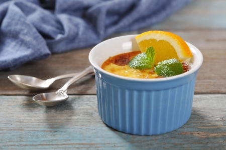 The creme brulee in ceramic baking mold with orange on wooden tableの写真素材