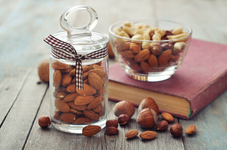 Almonds, walnuts, cashew and hazelnuts in glass bowls on wooden の写真素材