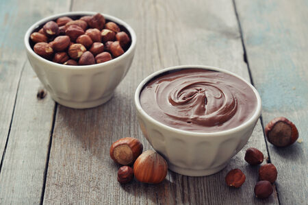 Hazelnut cream in ceramic bowl with hazelnut nuts on wooden の写真素材