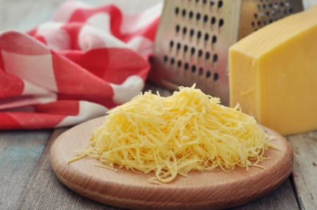 Grated cheese on wooden cutting board closeupの写真素材