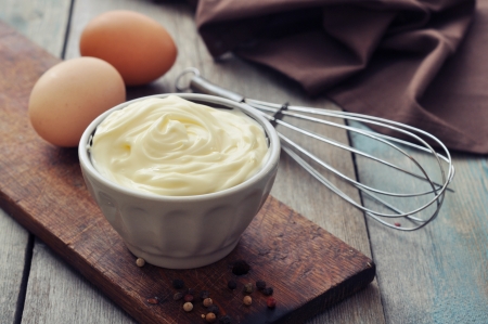 Homemade mayonnaise in bowl with eggs and spice on wooden backgroundの写真素材
