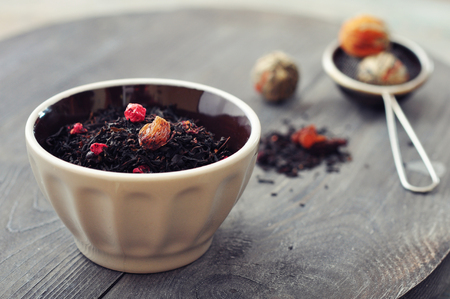 Dry tea with dried berries in ceramic bowl closeupの写真素材