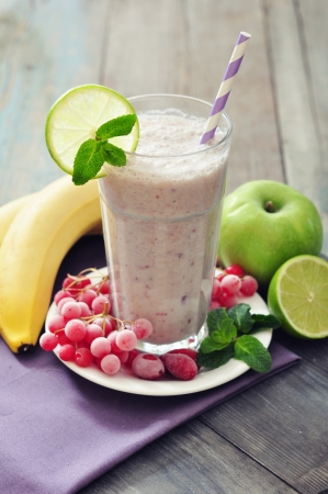 Banana smoothie  with berries, apple, lime and mint on wooden backgroundの写真素材