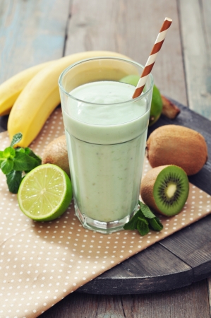 Banana smoothie with kiwi,  lime and mint on wooden backgroundの写真素材