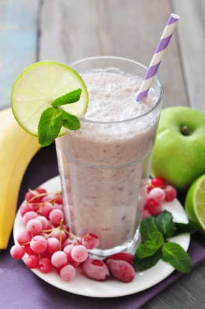 Banana smoothie  with berries, apple, lime and mint on wooden backgroundの写真素材