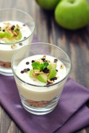 Homemade dessert with apple, nuts, yogurt and granola in glassesの写真素材