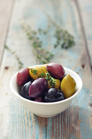 Different kinds of olives in bowl on wooden backgroundの写真素材