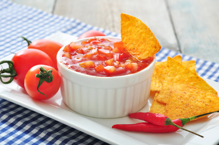 Bowl of salsa with tortilla chips, tomatos and chilli pepper on white dish closeupの写真素材