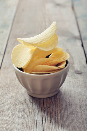 Potato chips in bowl on wooden tableの写真素材
