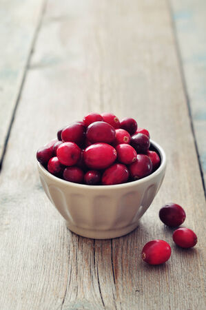Cranberries in ceramic bowl on wooden tableの写真素材