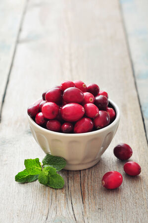 Cranberries in ceramic bowl on wooden tableの写真素材