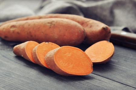 Raw sweet potatoes on wooden background closeup Raw sweet potatoes on wooden background closeup