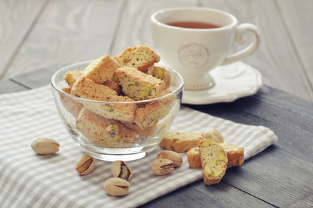 Fresh cantuccini with pistachios in glass bowl on wooden backgroundの写真素材
