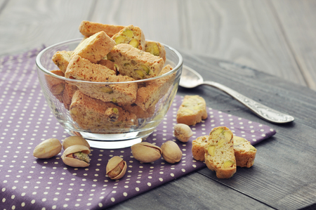 Fresh cantuccini with pistachios in glass bowl on wooden backgroundの写真素材