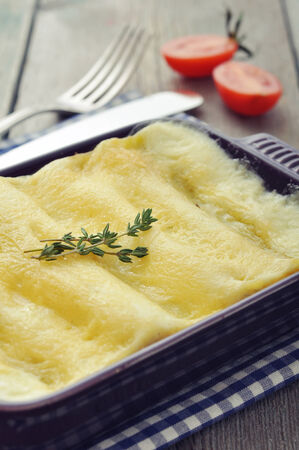 Cannelloni with ricotta and spinach in a baking dish on wooden backgroundの写真素材