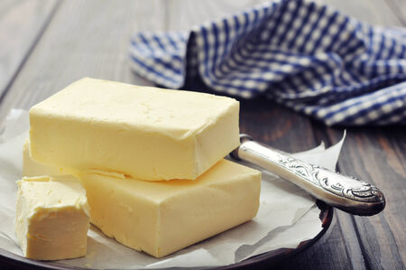 Fresh butter on wooden cutting board with knife closeupの写真素材