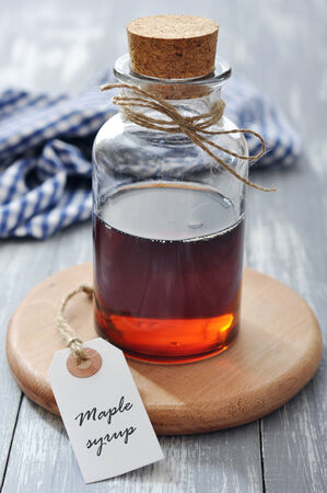 Maple syrup in glass bottle on a wooden backgroundの写真素材