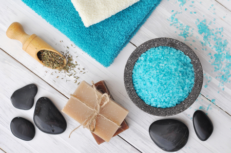 Spa composition with blue sea salt and massaging stones on white wooden の写真素材