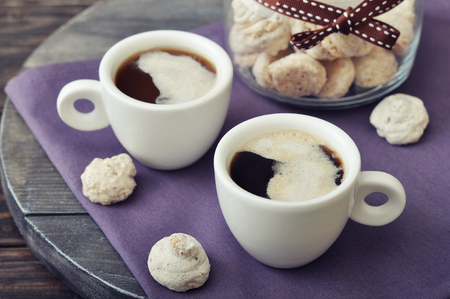 Cup of coffee with fresh biscotti in a glass jar on wooden backgroundの写真素材