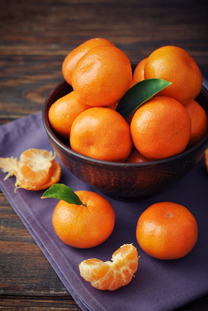 Bowl with fresh tangerines on a wooden backgroundの写真素材