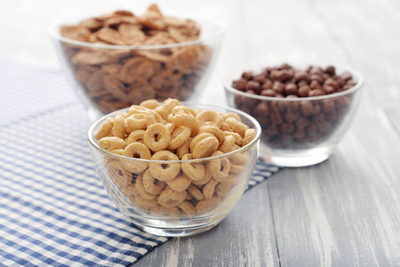 Various breakfast cereals in glass bowls on wooden background close-upの写真素材