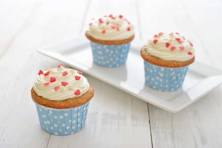 Cupcakes with icing in shape of hearts on wooden backgroundの写真素材