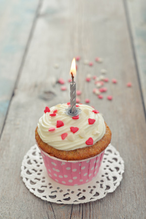 Birthday cupcake with candle on wooden backgroundの写真素材