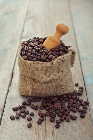 Sack of coffee beans with scoop on wooden background closeupの写真素材