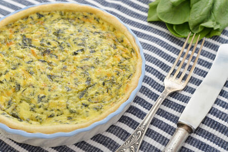 Traditional french quiche pie with spinach and cheese on wooden backgroundの写真素材