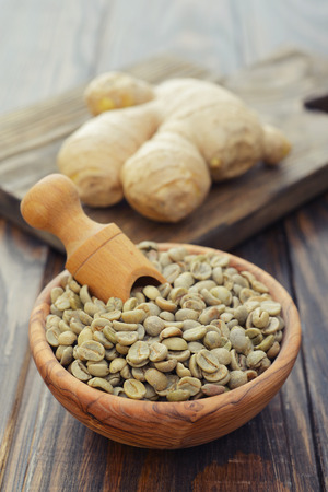 Green coffee beans  in wooden bowl with gingerの写真素材