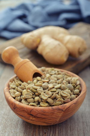 Green coffee beans  in wooden bowl with gingerの写真素材