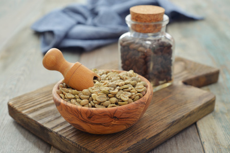 Green coffee beans  in wooden bowl with scoop on wooden backgroundの写真素材