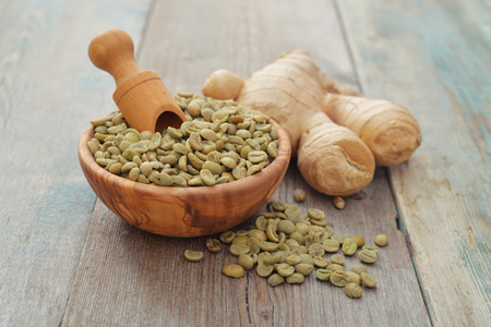Green coffee beans  in wooden bowl with gingerの写真素材