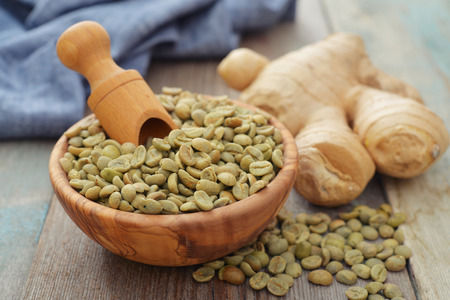 Green coffee beans  in wooden bowl with gingerの写真素材