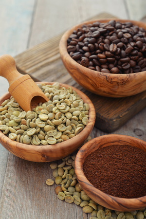 Green and roasted coffee beans  in wooden bowl closeupの写真素材