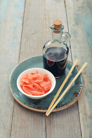 Pickled ginger with soy sauce and wooden chopsticks on plateの写真素材