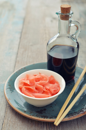 Pickled ginger with soy sauce and wooden chopsticks on plateの写真素材