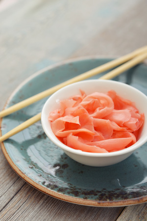 Pickled ginger with wooden chopsticks on plateの写真素材