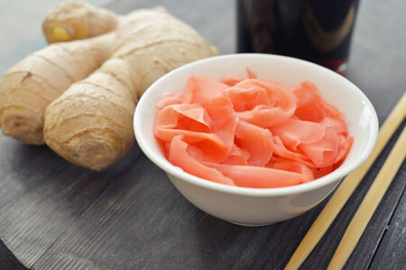 Pickled ginger with soy sauce and wooden chopsticks on plateの写真素材