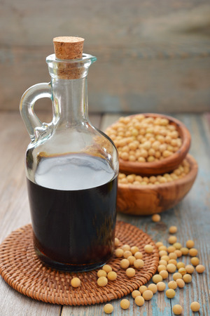 Soy sauce in a bottle with soy beans on wooden backgroundの写真素材