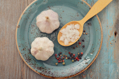 Garlic with pepper and salt on blue plate, top viewの写真素材