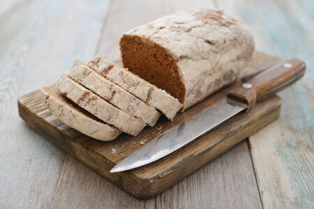 Sliced rye bread on cutting board closeup on wooden backgroundの写真素材