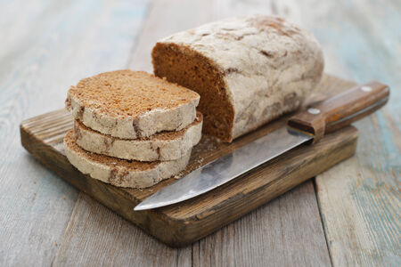 Sliced rye bread on cutting board closeup on wooden backgroundの写真素材